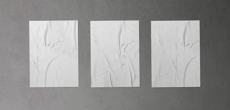 Pack of Three Crumpled Posters on Concrete Surface