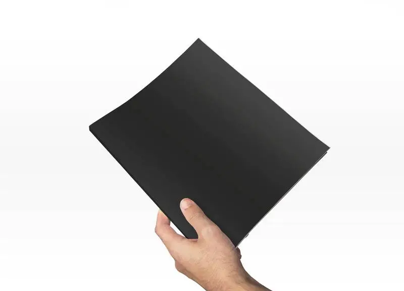 Hand Holding a Dark Magazine on a White Background