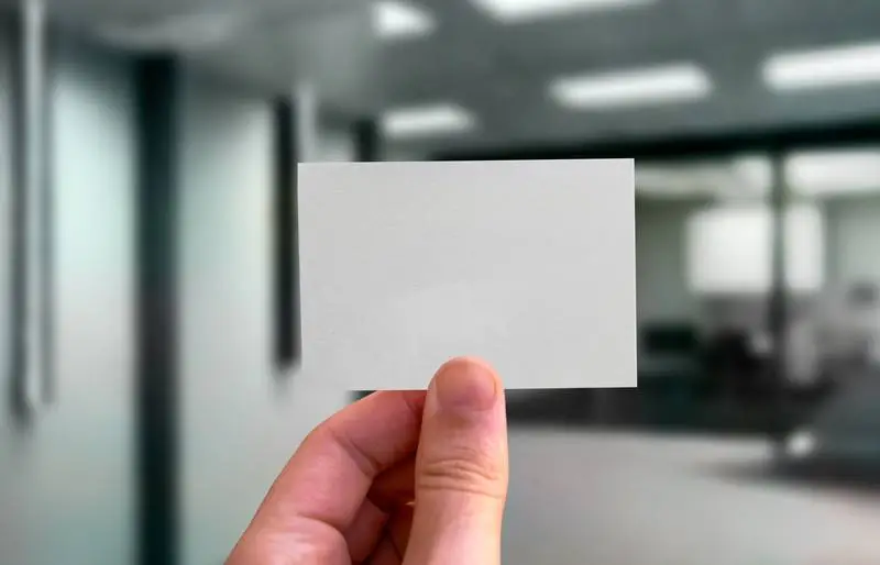 Hand Holding Business Card on Office Background