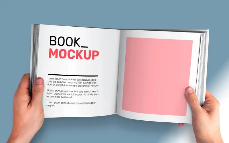 Mockup of Open Book Held by Two Hands on a Grey Background