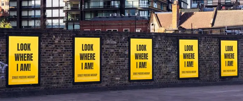 Mockup of Several Posters on a Brick Wall in a City