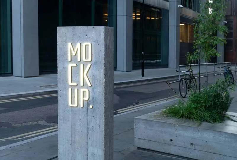 Illuminated Text on a Concrete Sign with a Modern Street