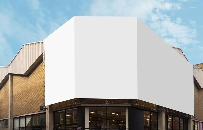 White Billboard for Mockup on Brick Building with Cloudy Sky Background