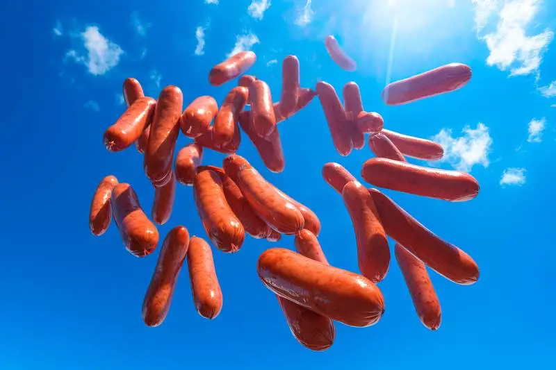 Composition Image of German Sausages Falling from the Sky on a Blue Background