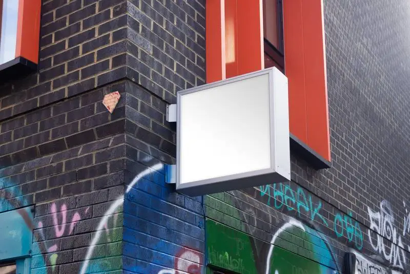 White Street Sign on Façade with Graffiti