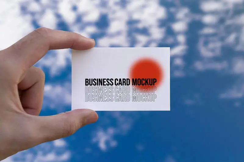 Mockup of a Hand Holding a Business Card with a Cloudy Sky in the Background