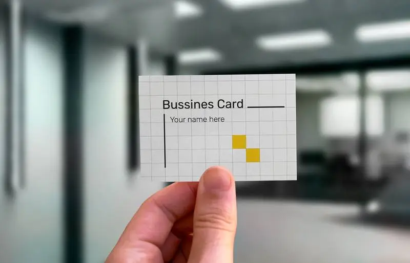 Hand Holding Business Card with Office Background