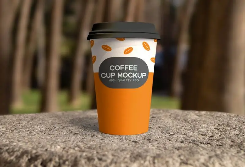 Mockup of Paper Coffee Cup in Outdoor Scene PSD
