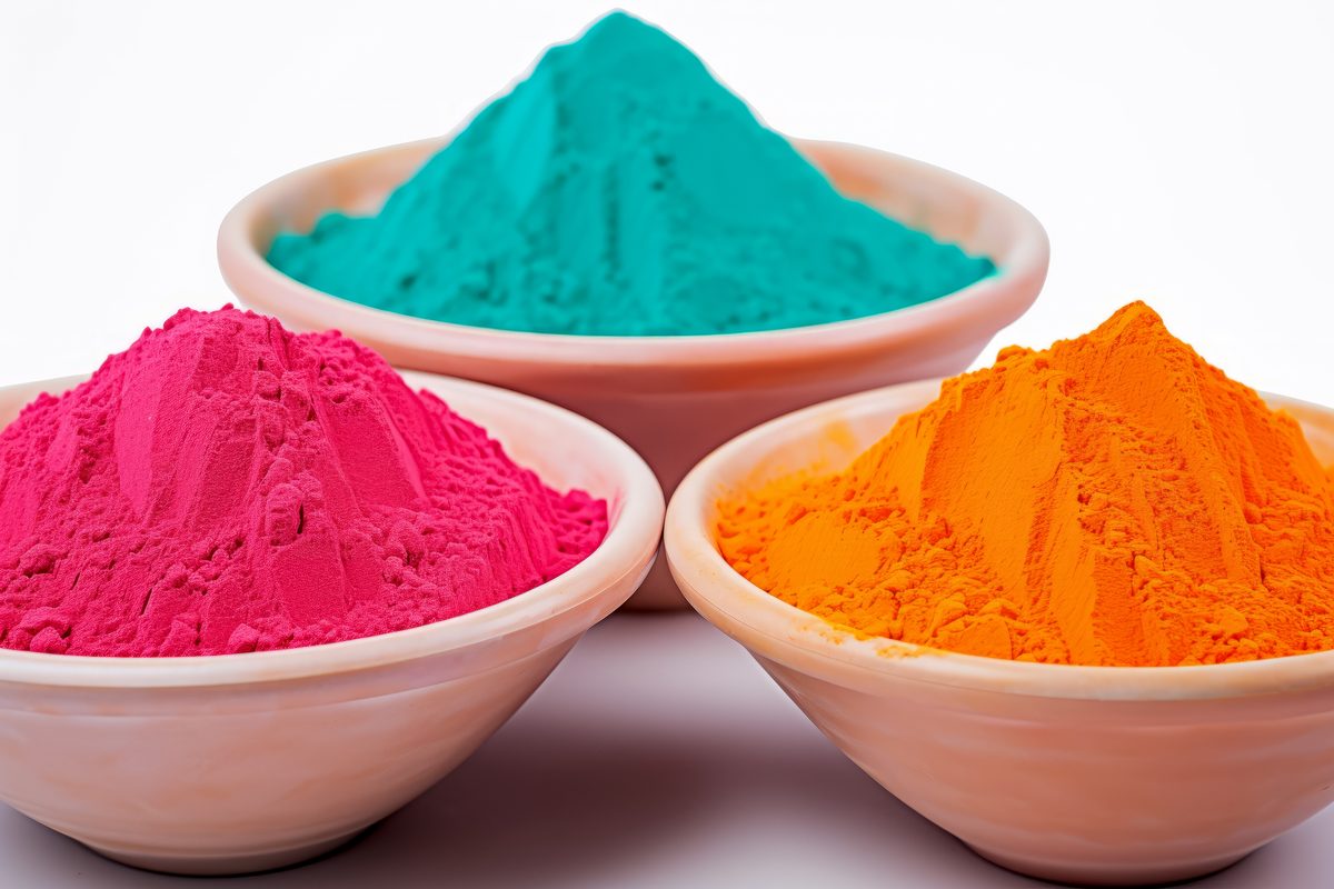 Bowls full of intensely coloured powder on white background for Holi Festival