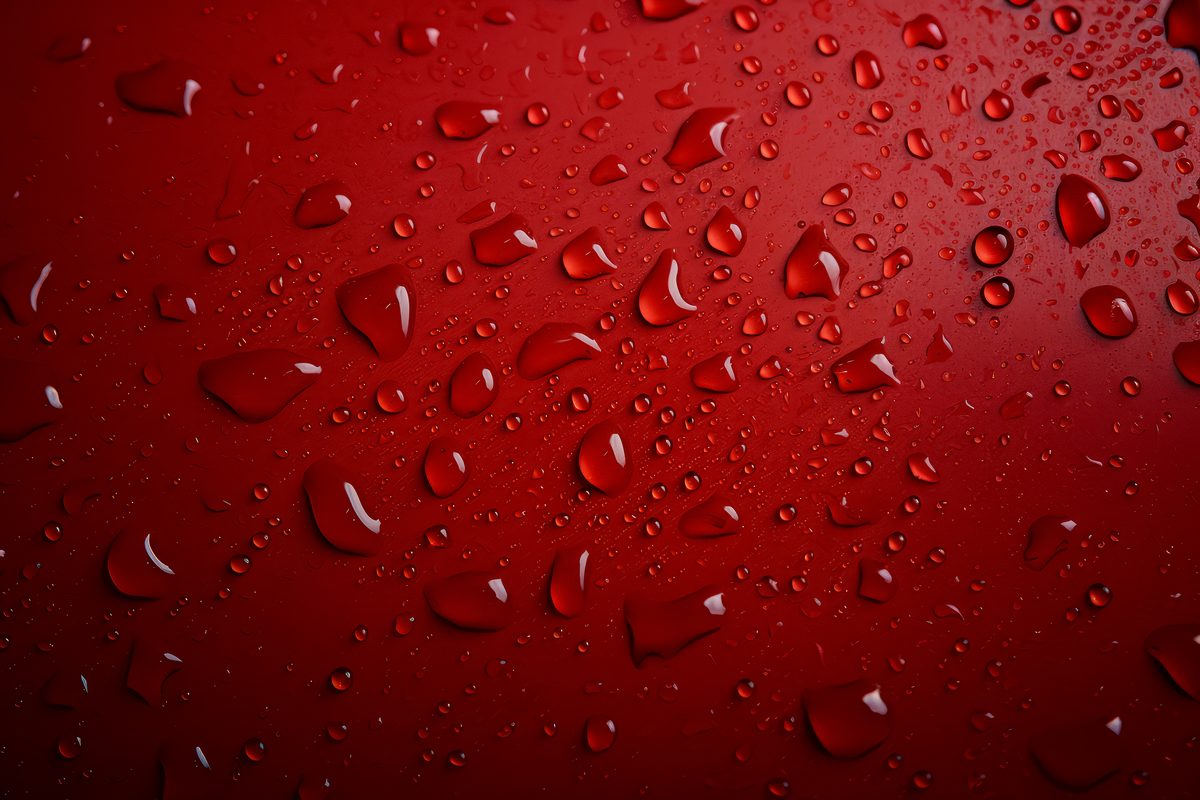Photo of water droplets splashed on a red surface