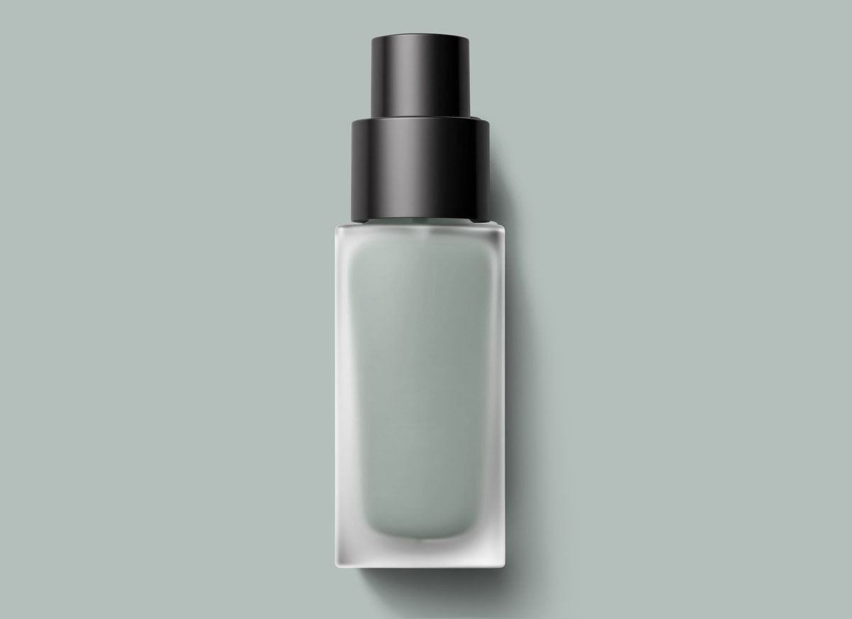 Cosmetic glass jar with black cap on pastel green surface