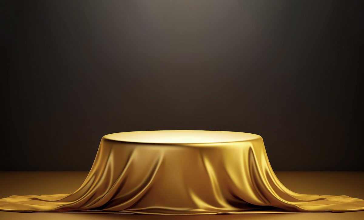 Empty podium covered with a golden cloth for product presentation on a dark background