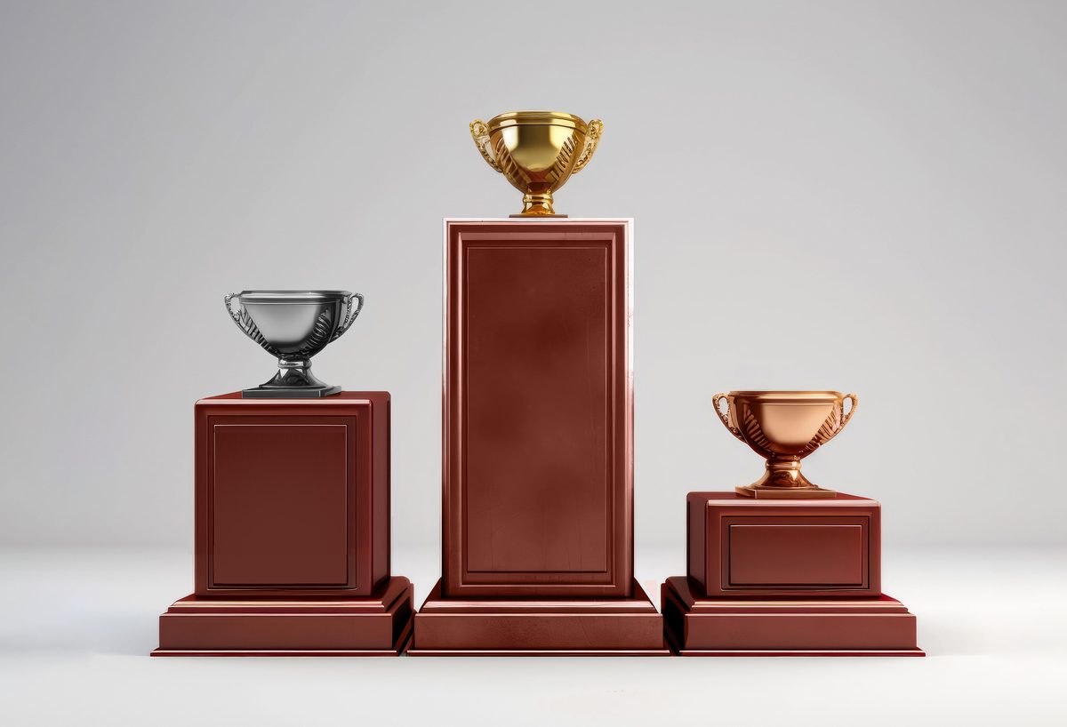 Three podiums with gold, silver and bronze cups on a grey background